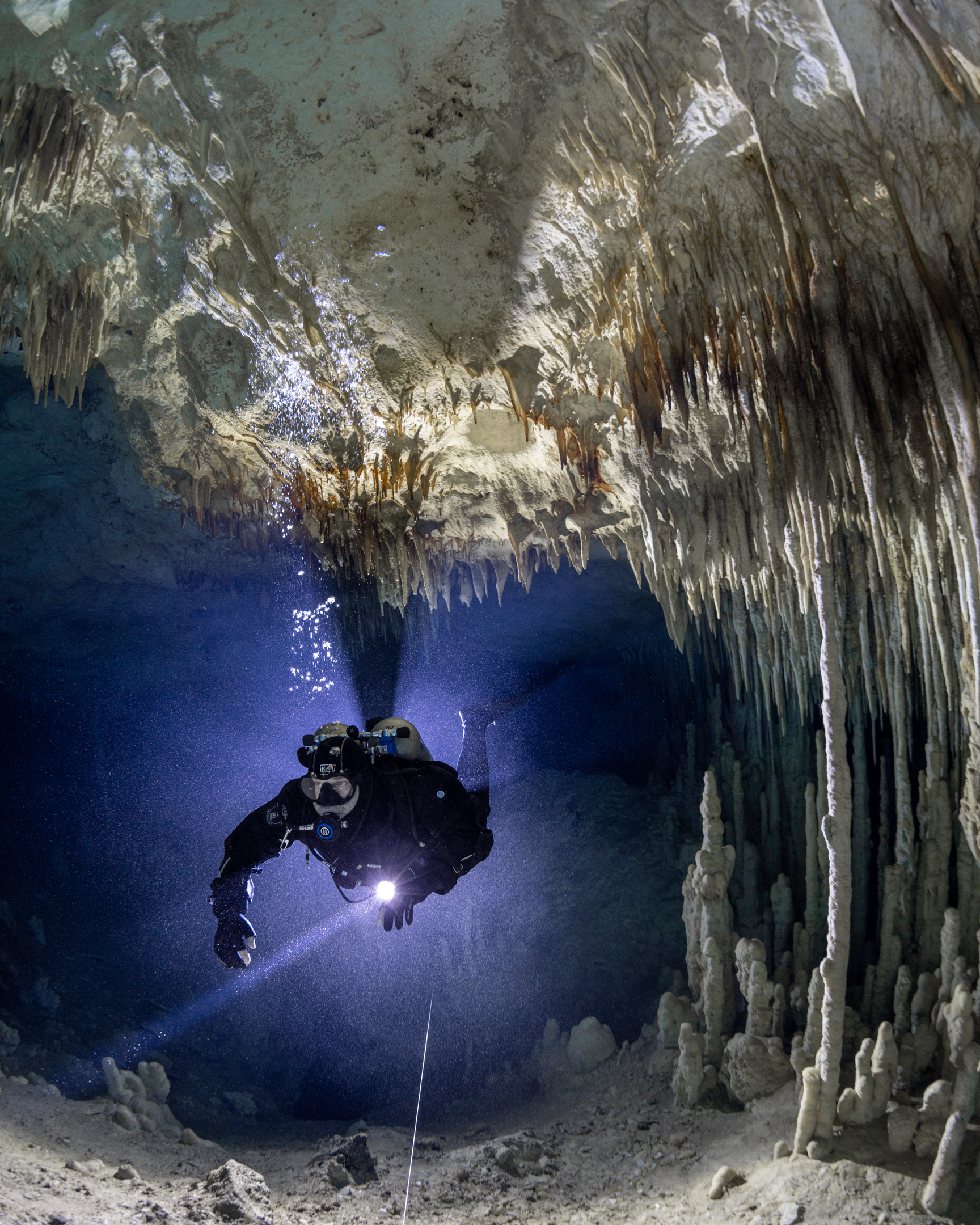 Cave diver swimming beneath limestone formations